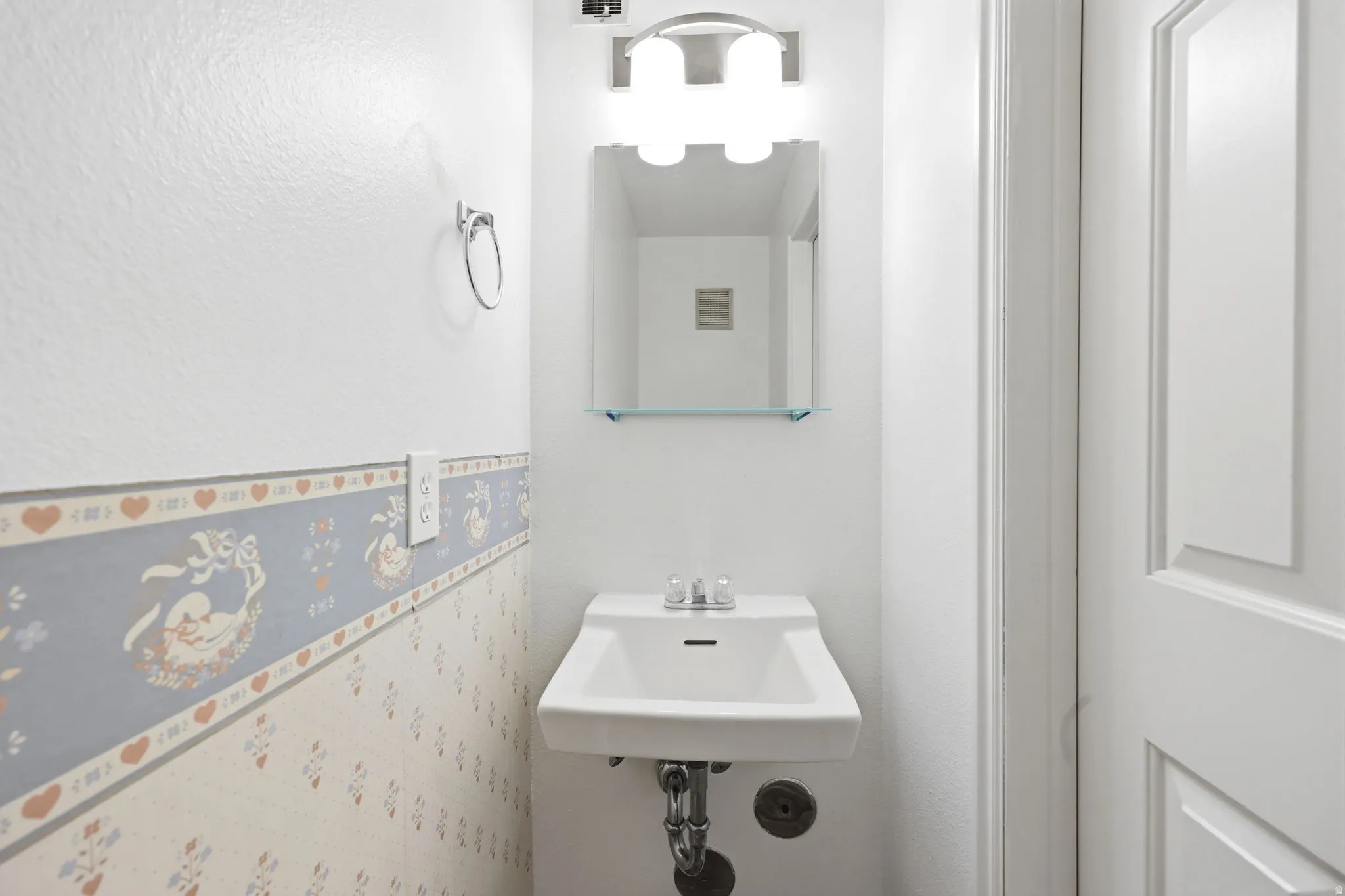 Pedestal sink with chrome fixtures, mirror with glass shelf, and a four-bulb vanity light