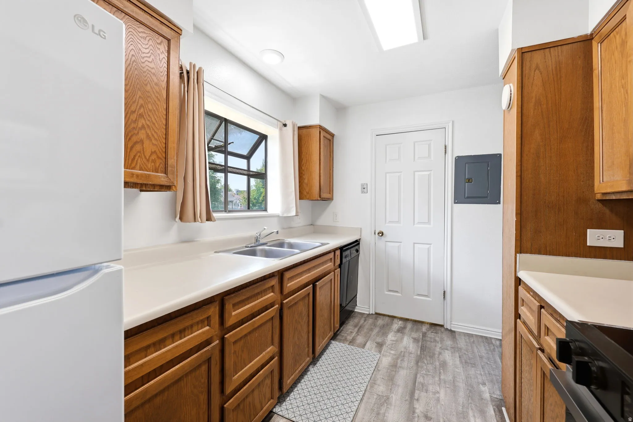 Kitchen featuring wood-finish cabinetry, solid surface countertops, and wood-finish flooring