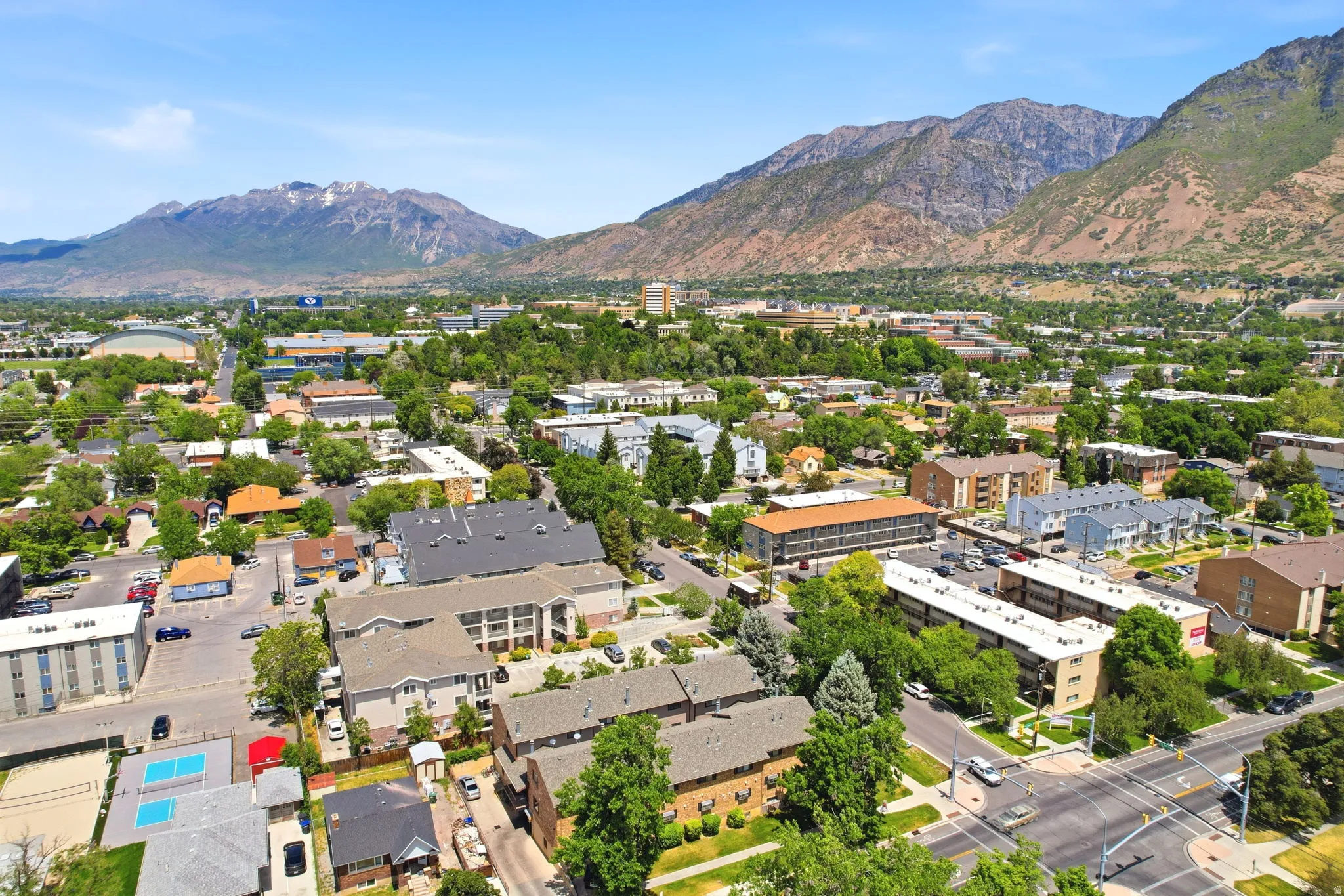 Expansive aerial perspective showcasing a varied urban landscape with prominent mountain backdrops