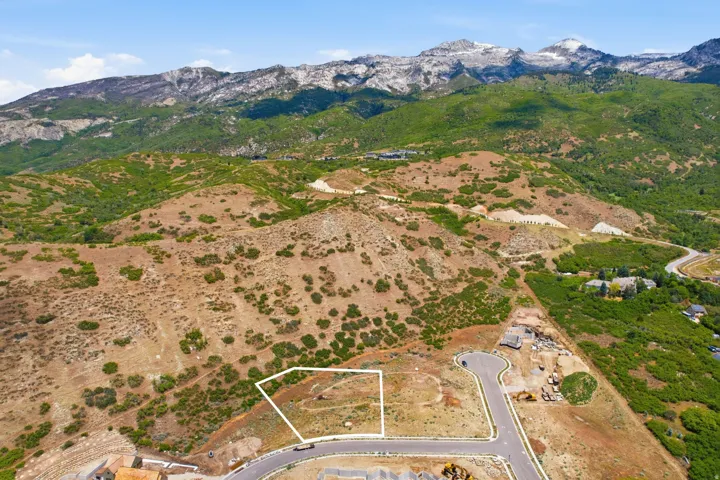 Cleared building lot outlined in white, featuring mountain and hillside surroundings