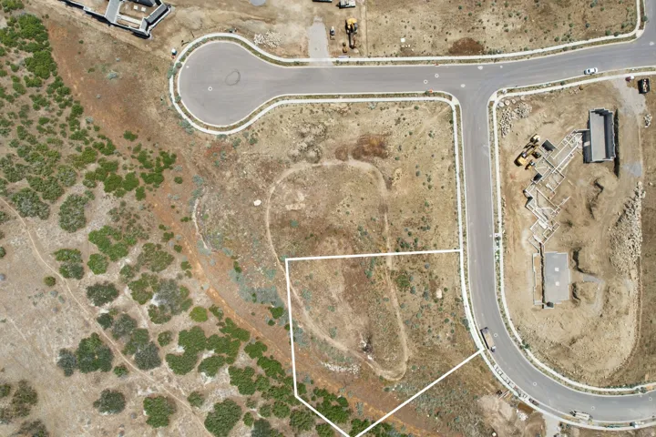 Expansive undeveloped lot featuring a defined perimeter, bordered by natural terrain, and access to paved roadways