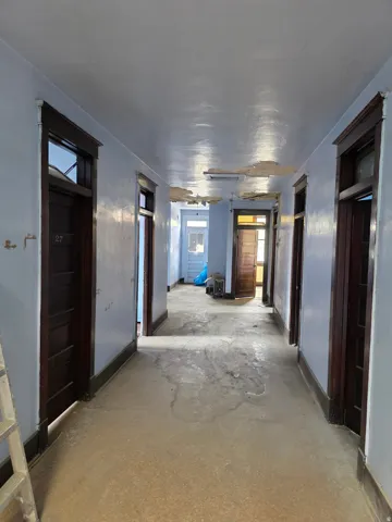Long hallway featuring multiple dark wood-finish doors with transoms