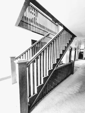 Multi-level wooden staircase featuring sturdy balusters, a robust handrail, and broad newel posts