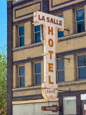 Vintage-style hotel sign with "La Salle Hotel Cafe" lettering, featuring a brown background and orange text