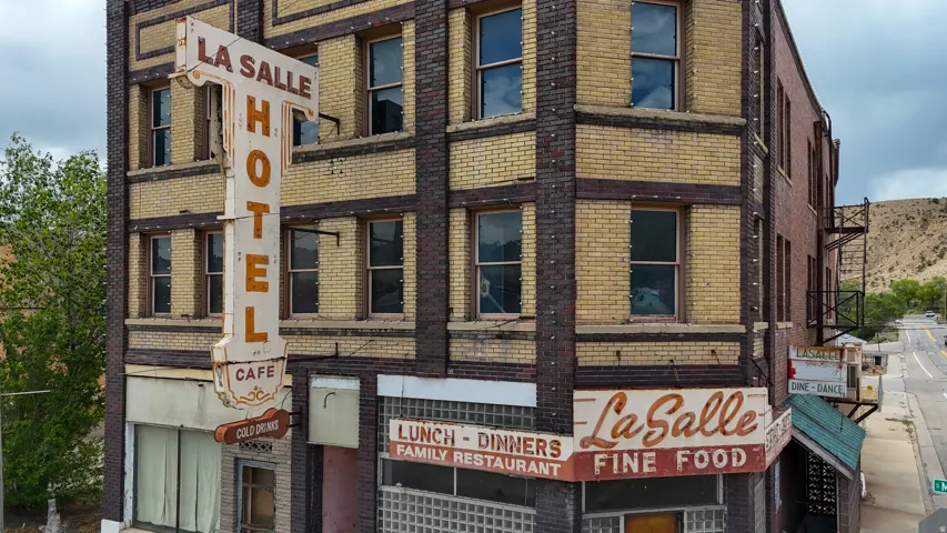 Brick facade building with a prominent vintage vertical sign, corner entrance, and street-level commercial storefronts