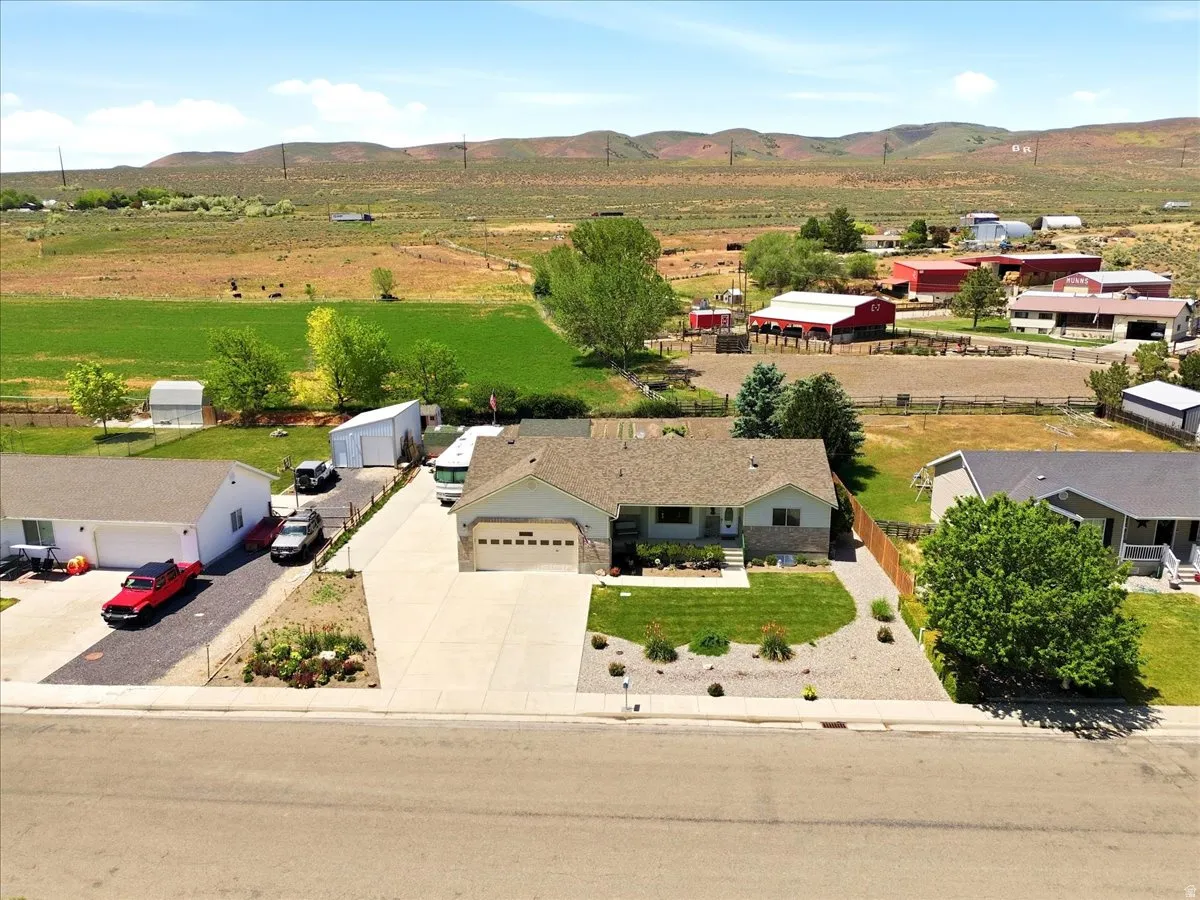 Ranch-style residence featuring an attached two-car garage, concrete driveway, and a landscaped front yard with lawn and decorative rock