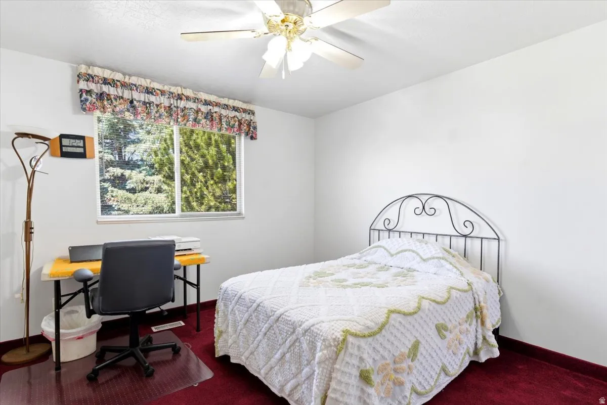 Bedroom featuring a window with a valance, a ceiling fan, and red carpeting