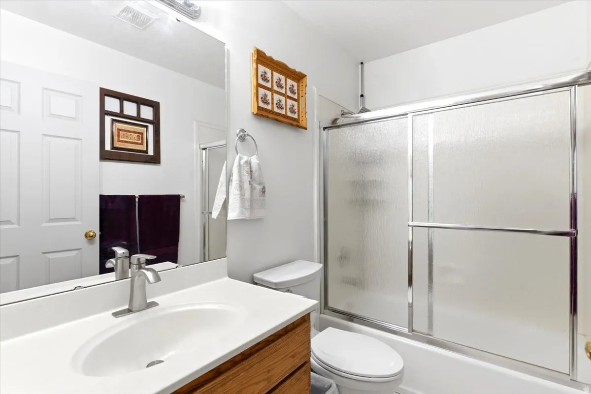 Bathroom featuring a wood-finish vanity with a white countertop and integrated sink, brushed nickel faucet, and a large wall-mounted mirror