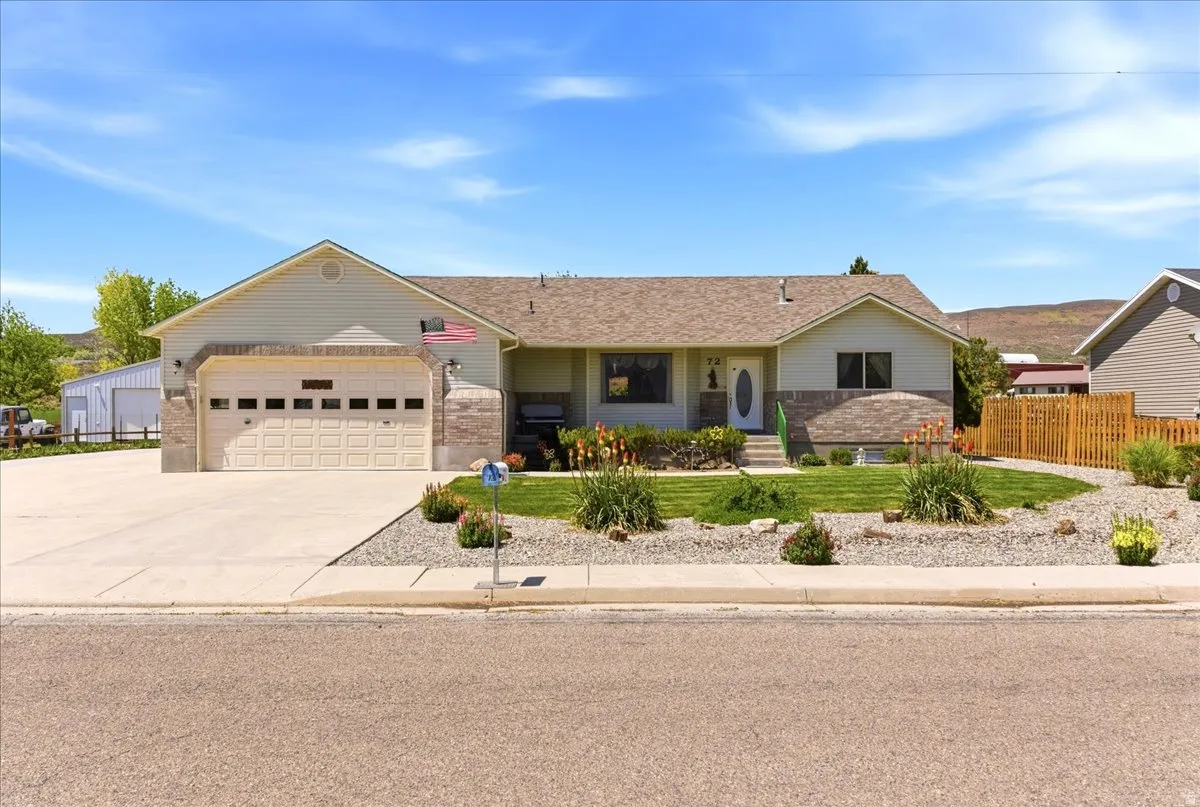 Ranch-style residence featuring a two-car garage, concrete driveway, stone accents, a fenced yard, and landscaped front gardens