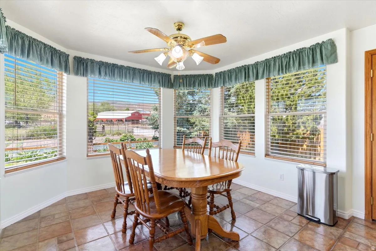 Dining area featuring a bay window with multiple panes, ceramic tile flooring, and a ceiling fan with integrated lighting