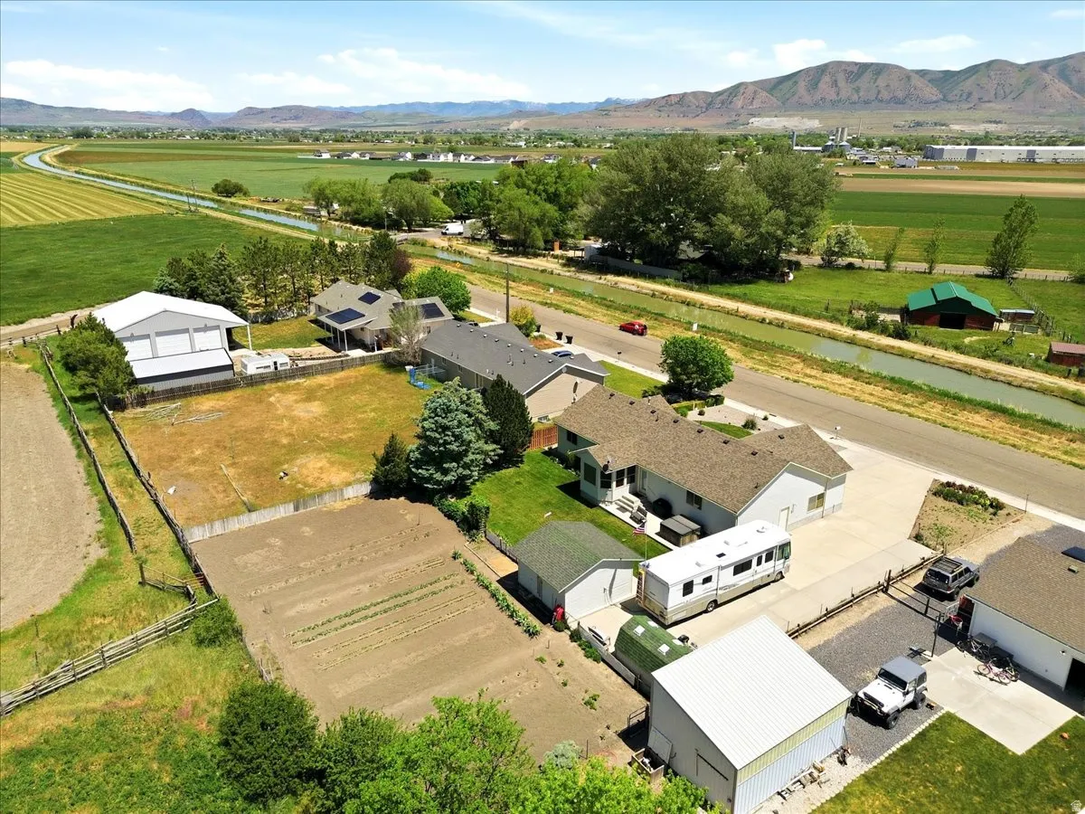 Expansive property featuring a cultivated garden plot, a large fenced yard, and multiple outbuildings