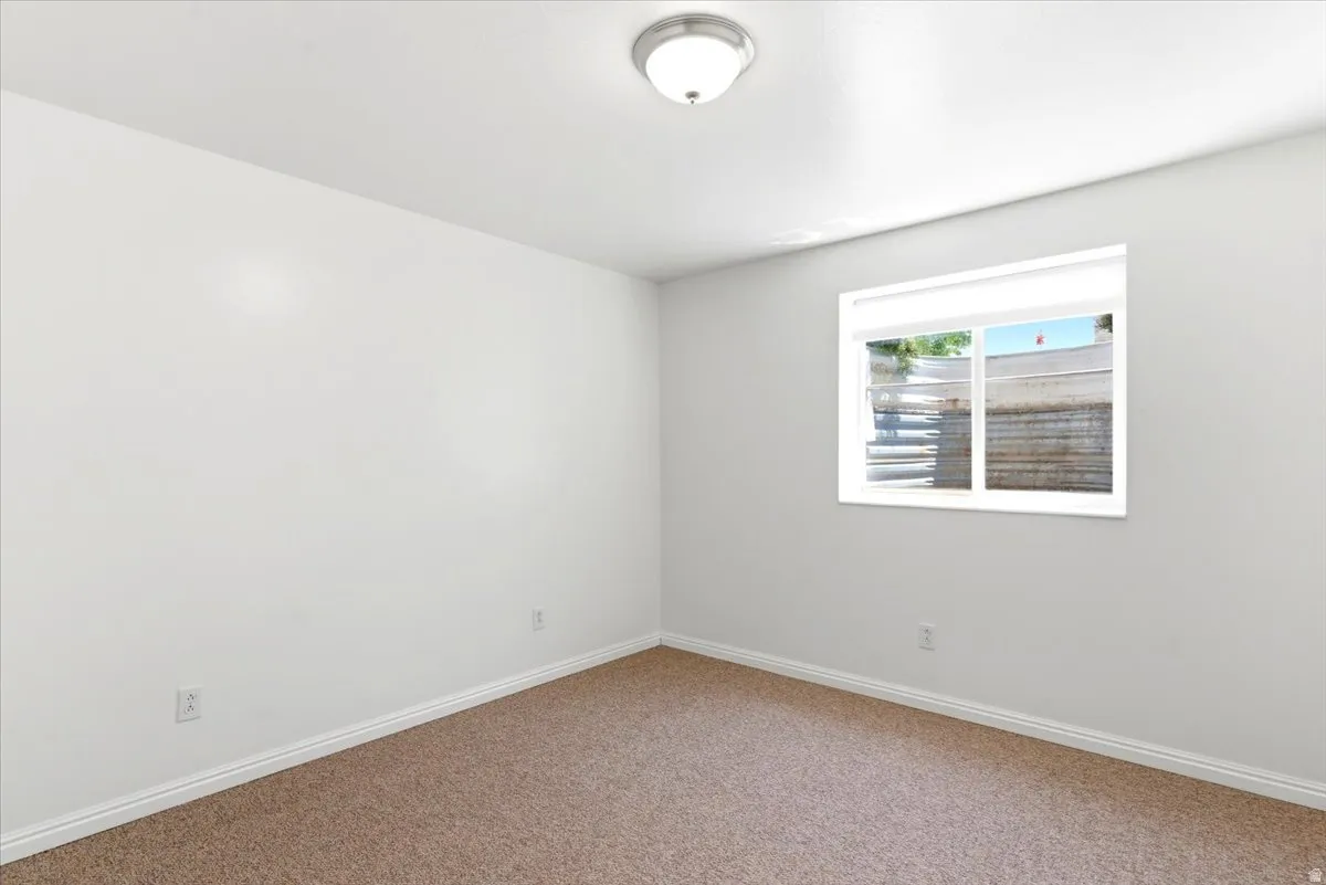 Room featuring neutral-toned carpet flooring, white walls, and a single window