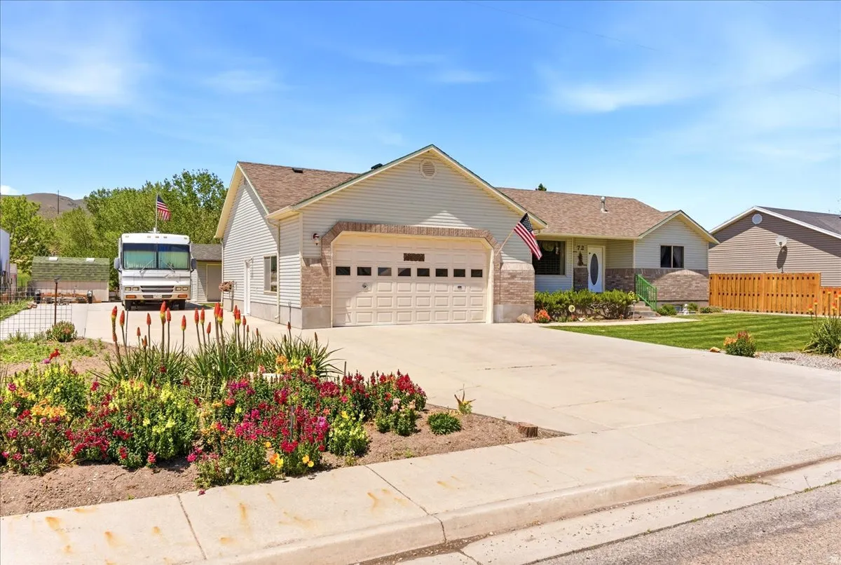 Single-story exterior featuring light-colored siding, an attached garage, and a concrete driveway