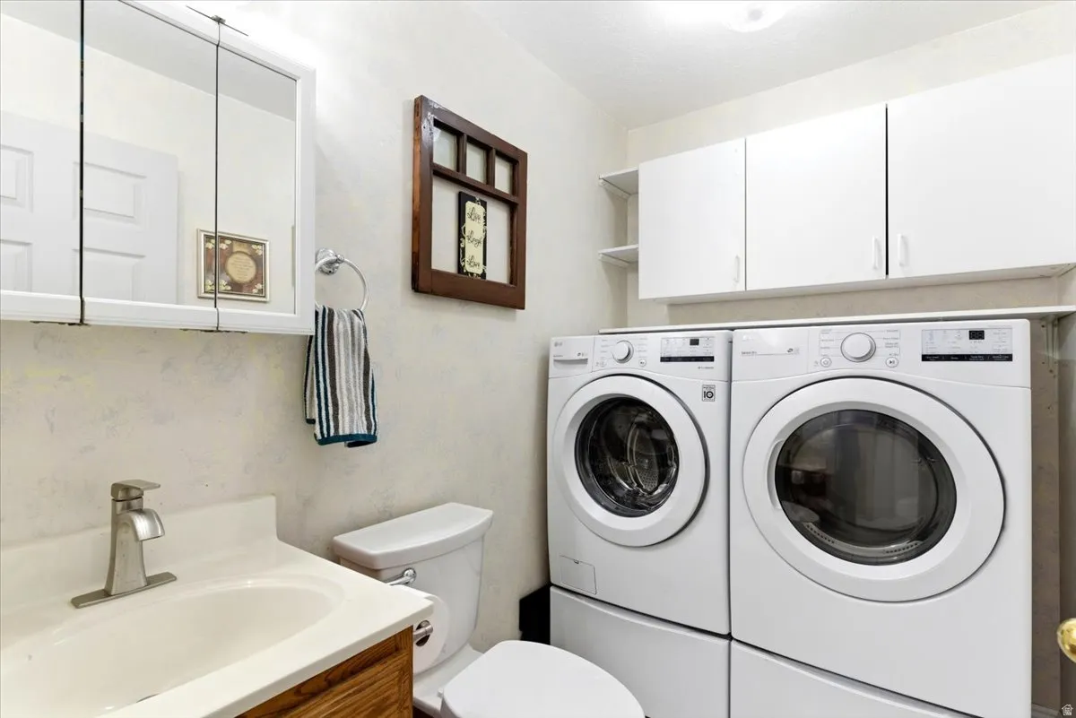 Laundry area with a front-load washer and dryer, complemented by overhead white cabinetry