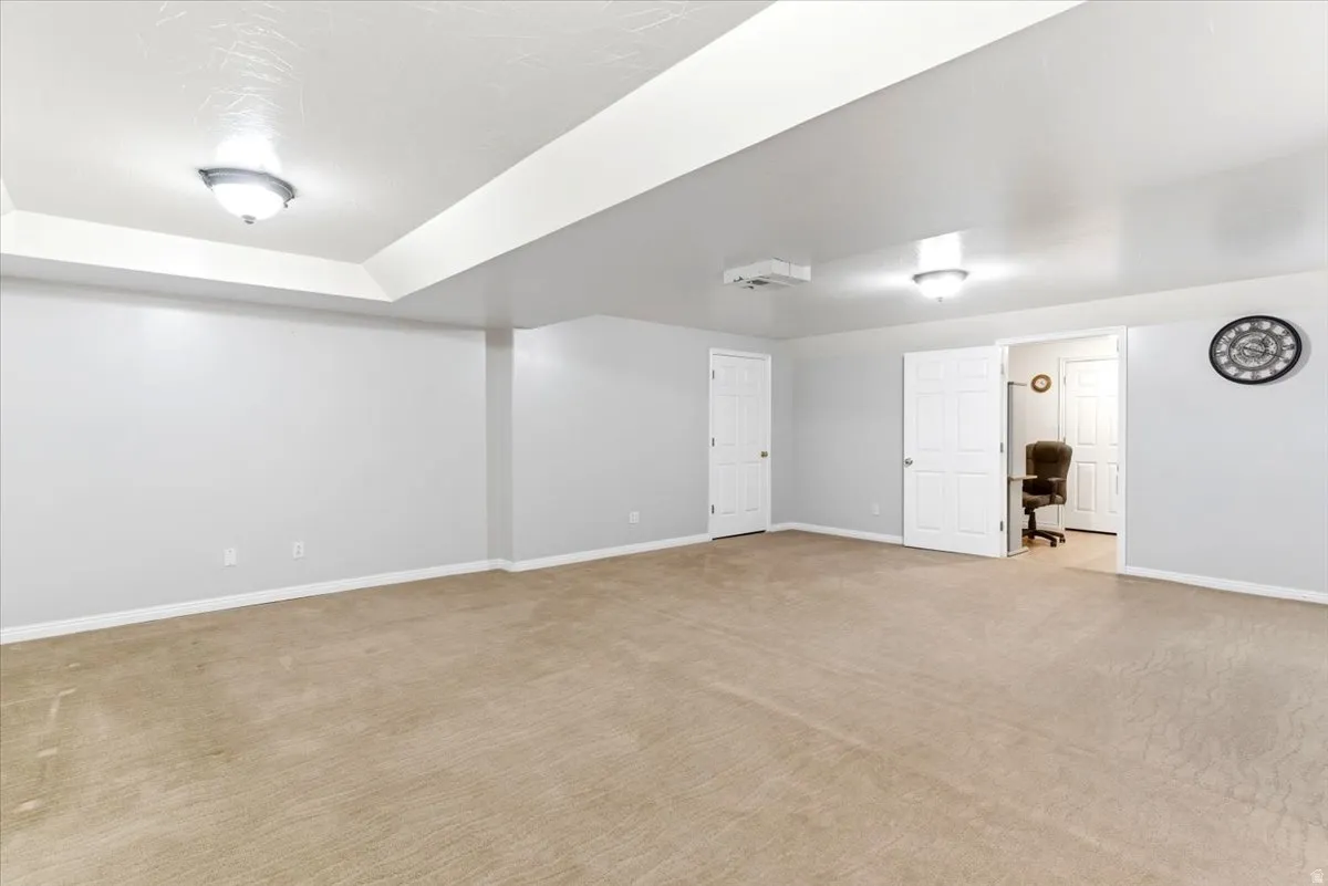 Spacious carpeted room featuring recessed lighting, a ceiling-mounted projector, and neutral gray walls with white trim