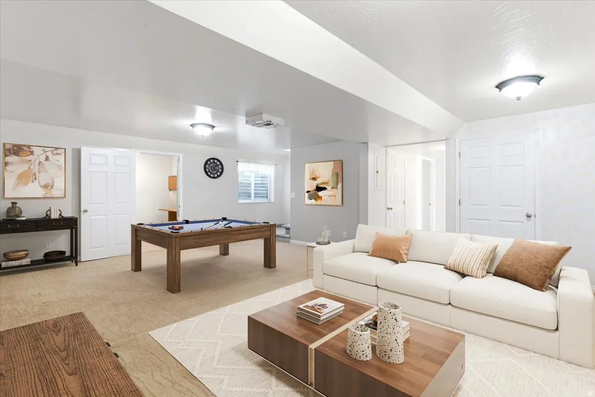 Spacious lower-level area with recessed and flush-mount lighting, featuring a billiards table, multiple doorways, and a window with blinds