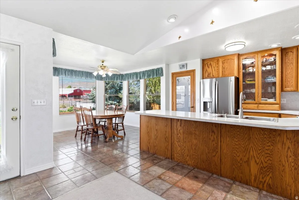 Bright kitchen and dining area featuring natural wood cabinetry, stainless steel refrigerator, white countertops, and tiled flooring