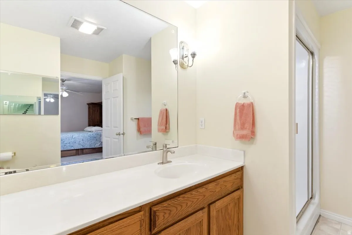 Bathroom vanity featuring a single sink, light-toned countertop, wood-finish cabinetry, and an overhead sconce light fixture