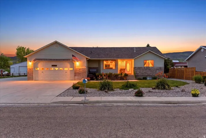 Single-story residence featuring a two-car garage with overhead lighting, a concrete driveway, and a stone facade foundation