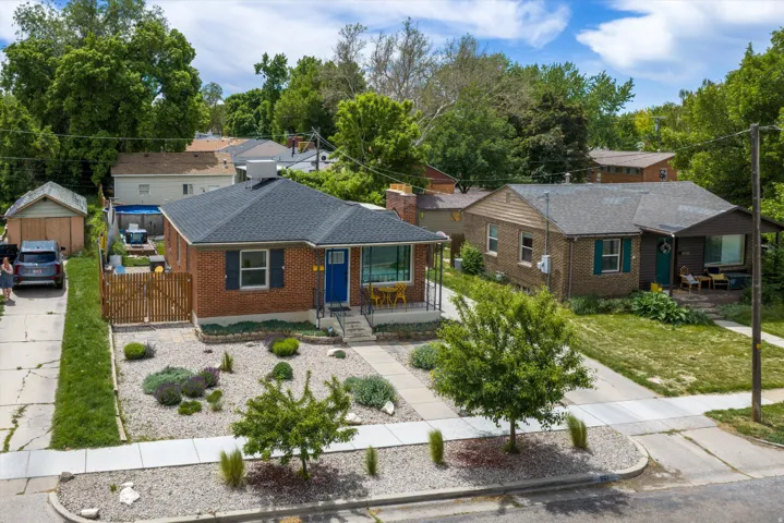 Brick facade home featuring a contrasting blue entry door, dark roof shingles, and a front yard with gravel landscaping