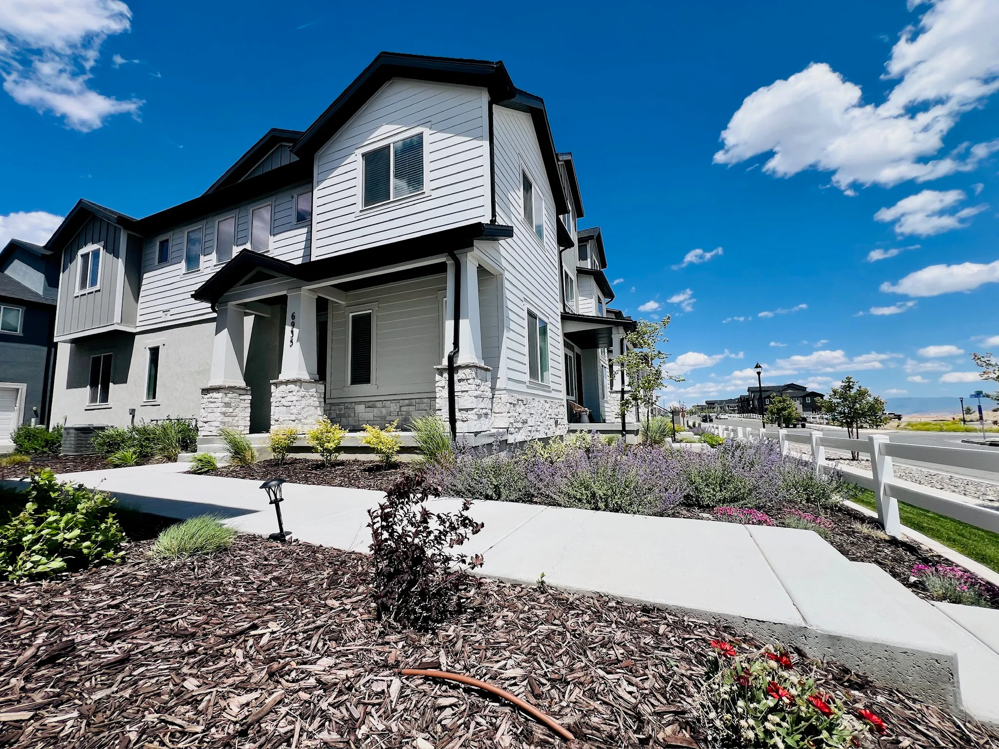 Modern townhouse exterior featuring light-colored siding and dark trim