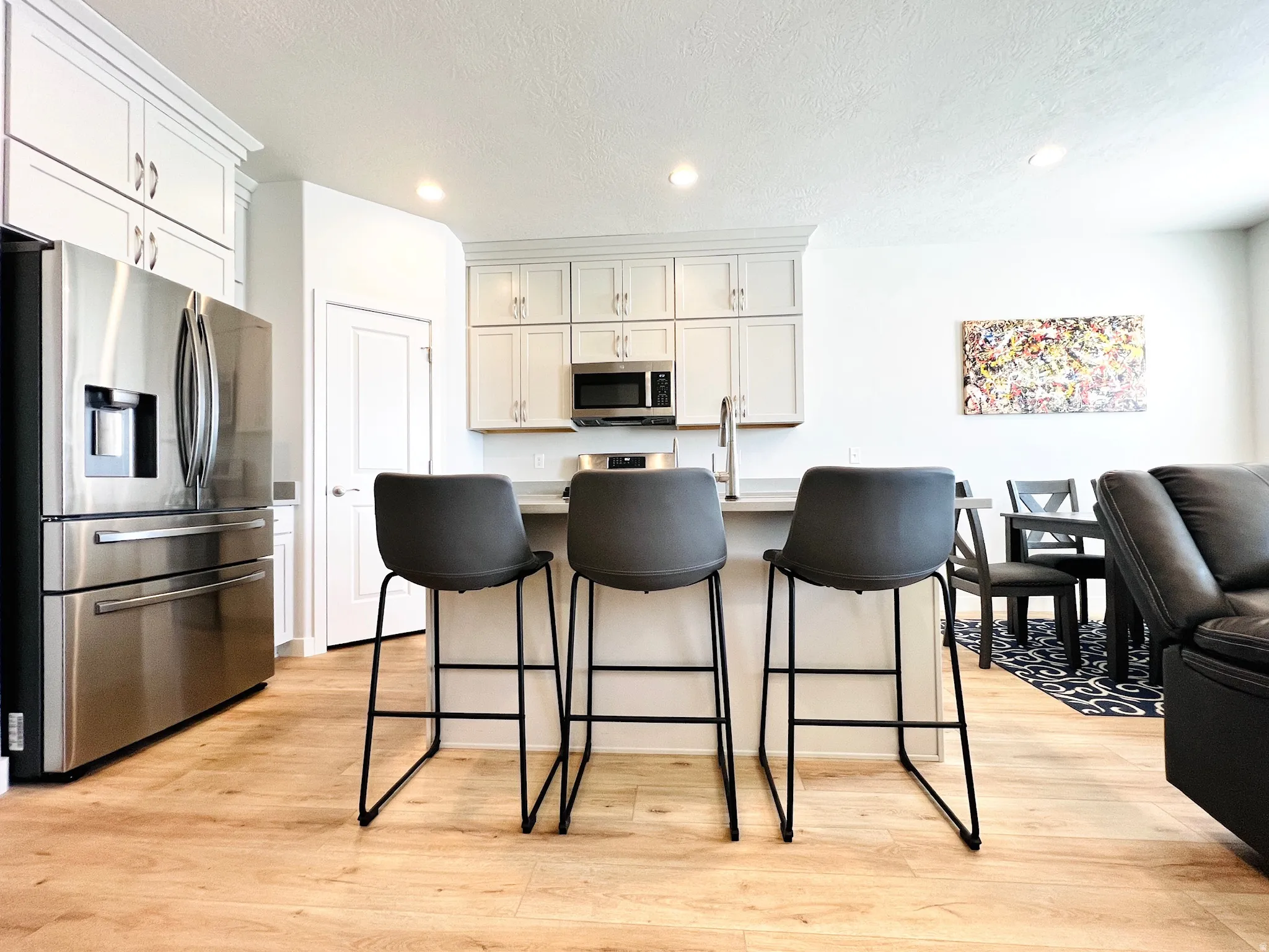 Kitchen island with light-toned countertop, stainless steel appliances, and wood-finish flooring