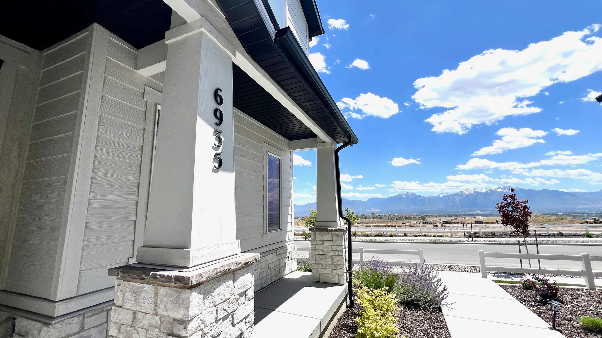 Covered porch entry featuring stone accent pillars and light-toned siding