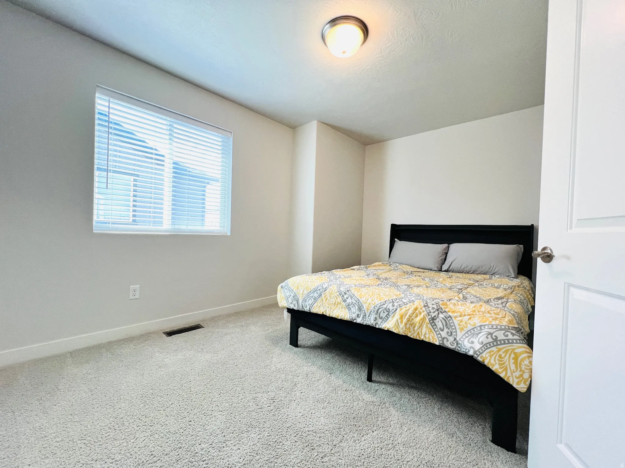Bedroom featuring light-toned carpeting, a window with blinds, and white walls