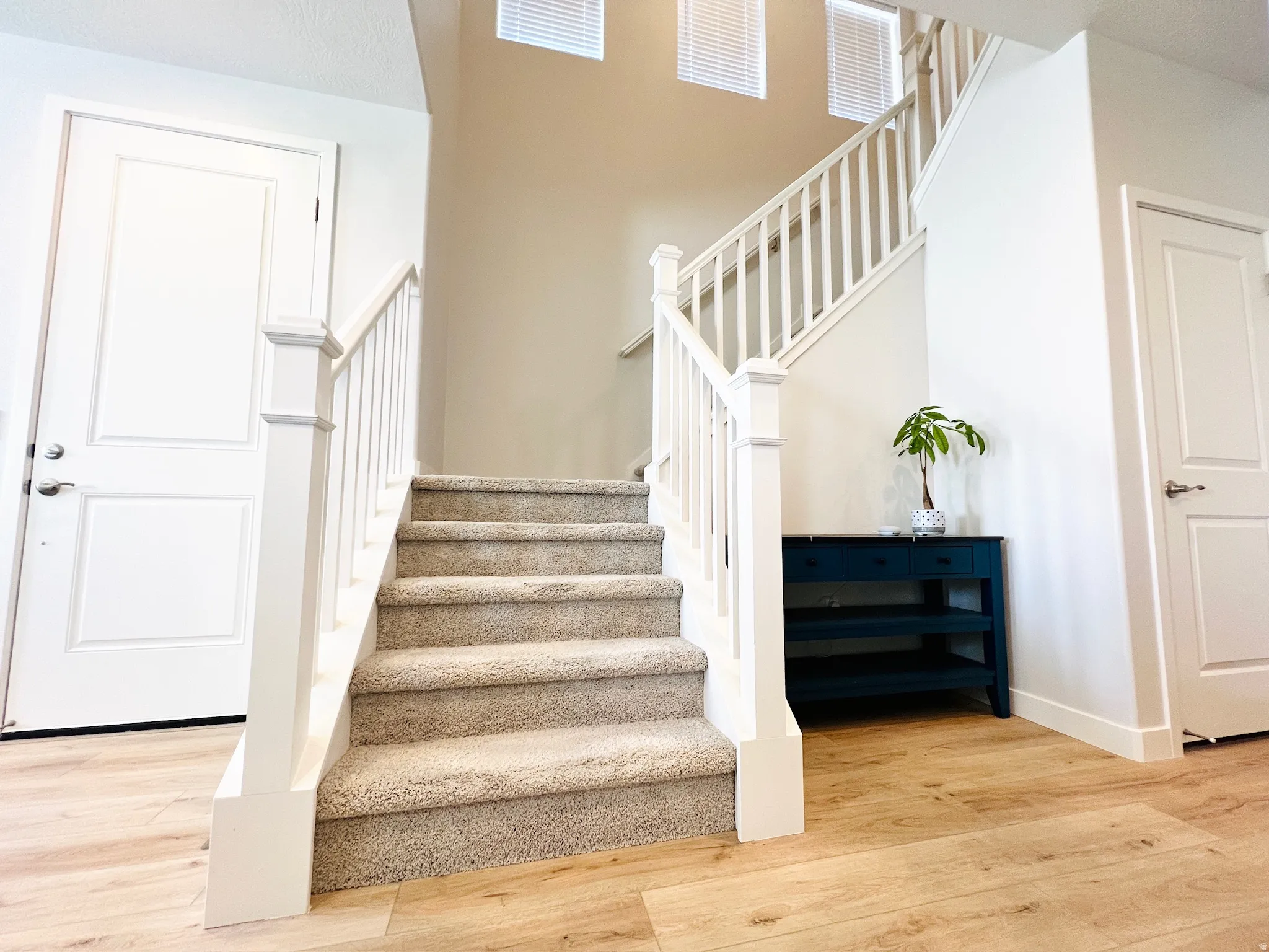 Staircase featuring carpeted treads and white wood balusters and newel posts