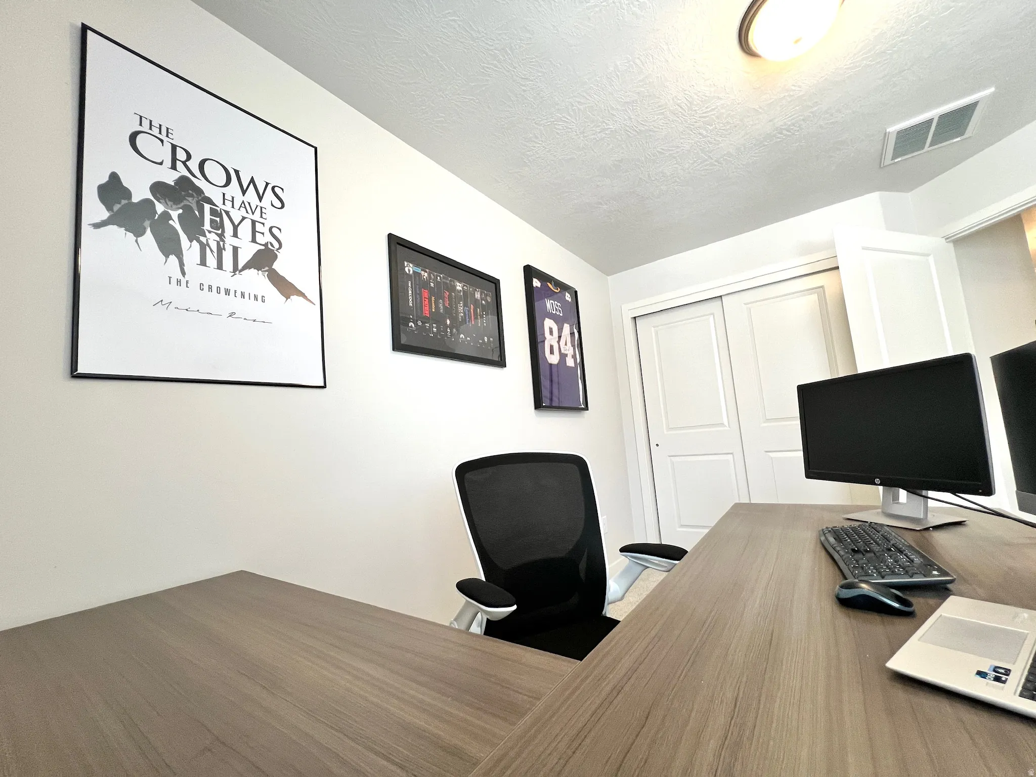Workspace featuring a wood-finish L-shaped desk and white walls