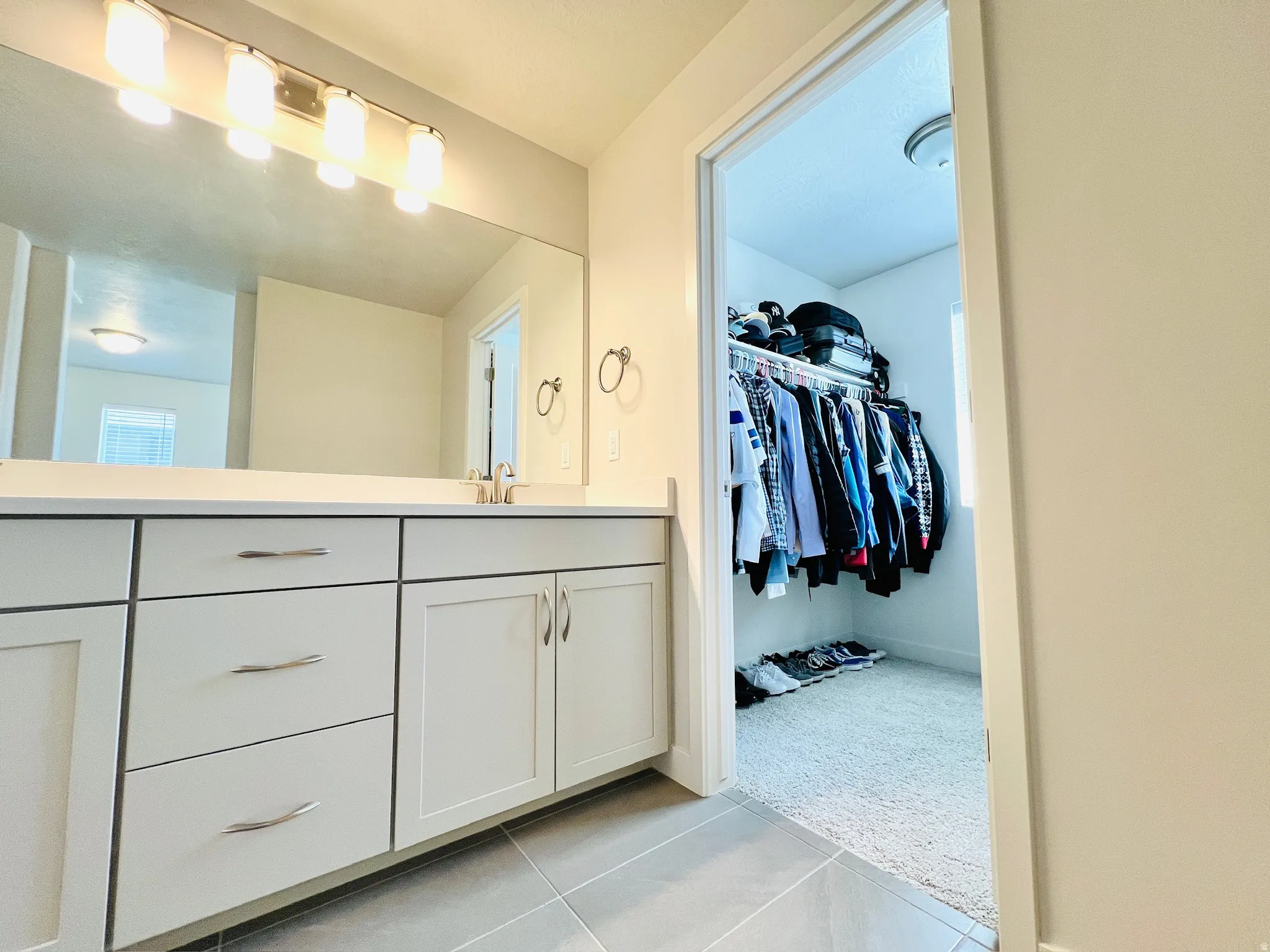 Bathroom vanity featuring light-toned cabinetry with brushed nickel hardware, a white countertop, and a large wall-mounted mirror