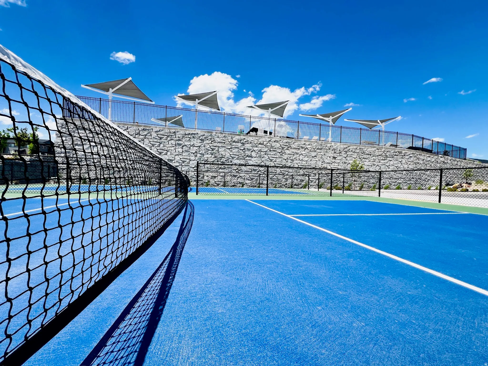 Regulation-size tennis court featuring vibrant blue and green surfacing with white line markings