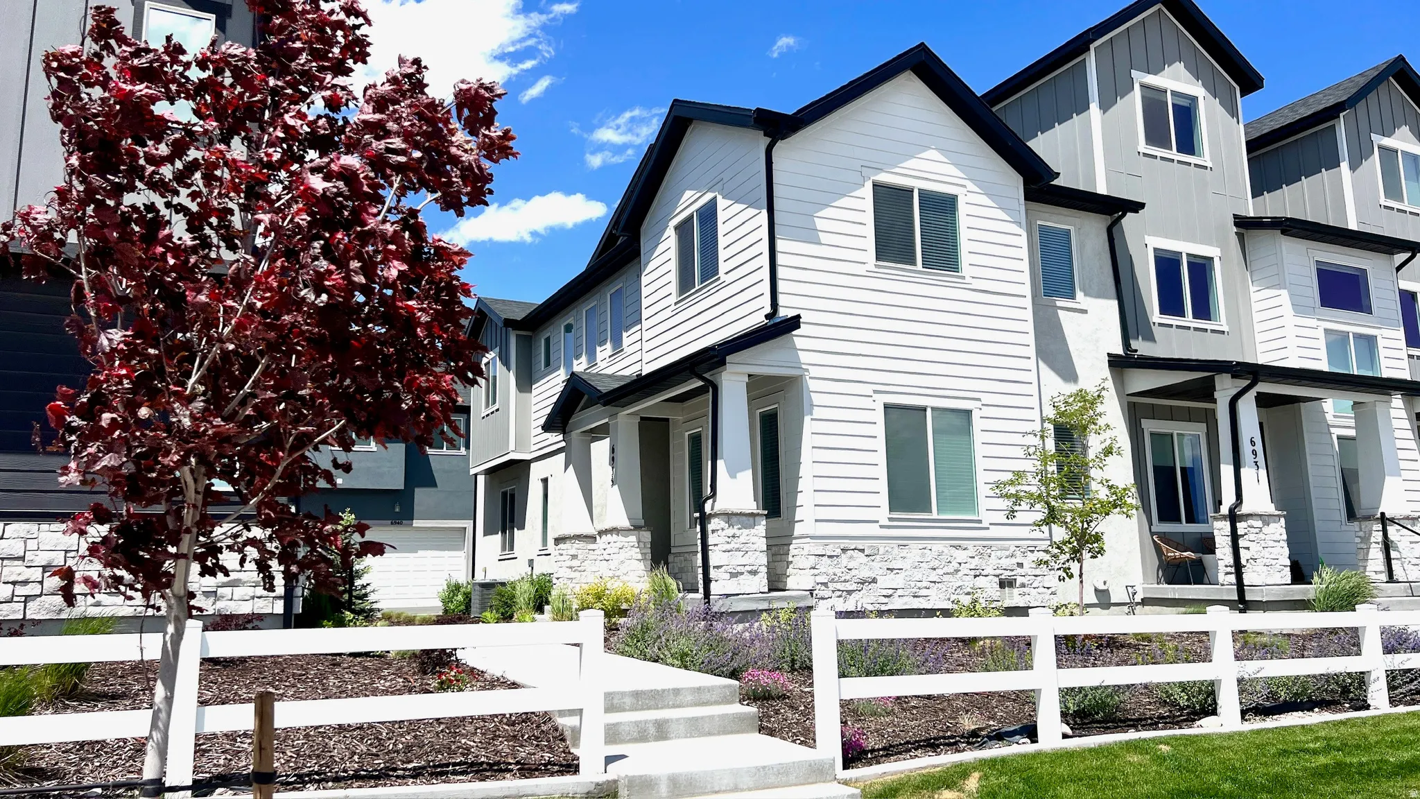 Modern townhome exterior featuring white horizontal siding and a black gabled roof