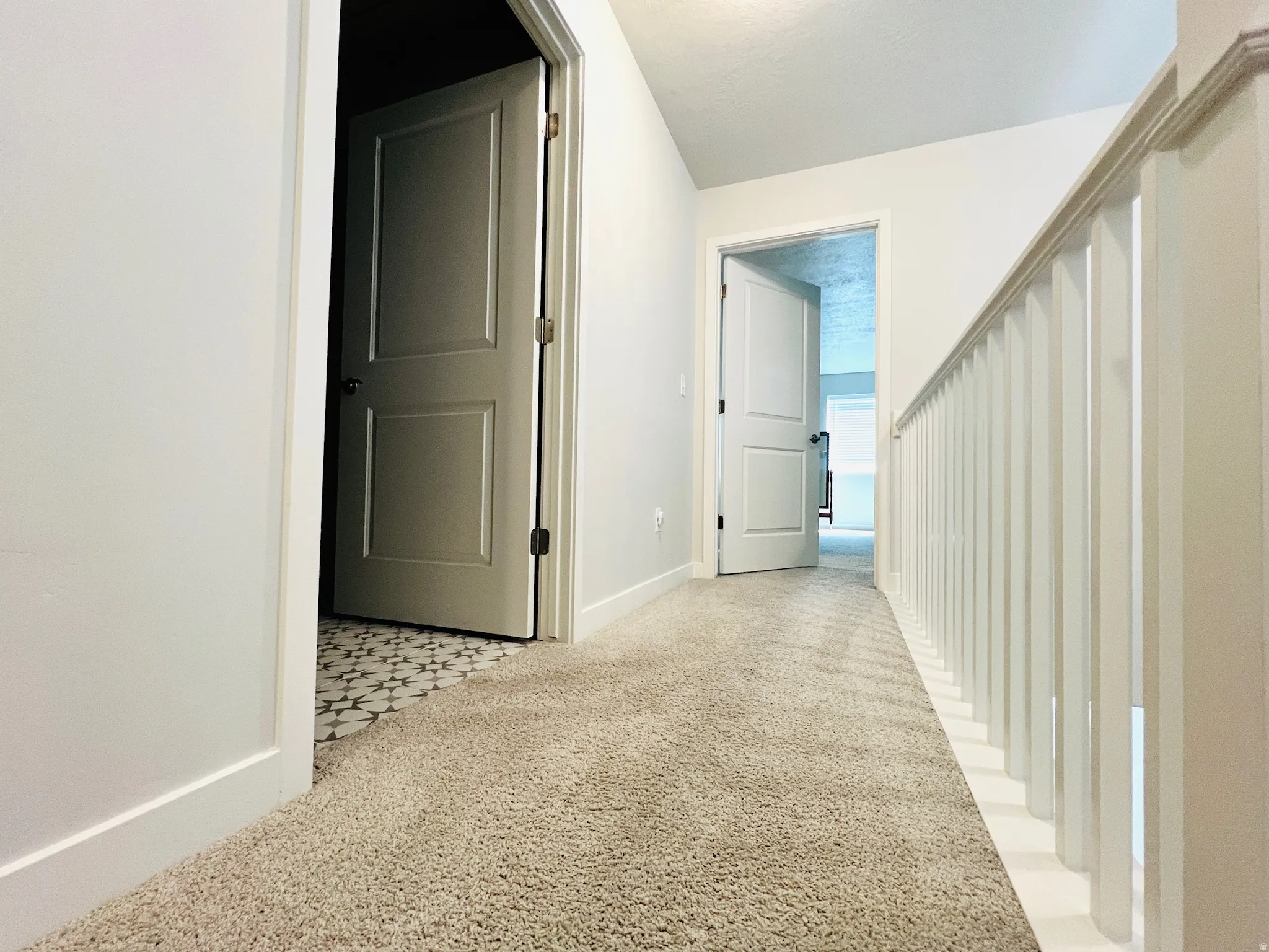 Carpeted hallway with white trim, leading to rooms with solid panel doors