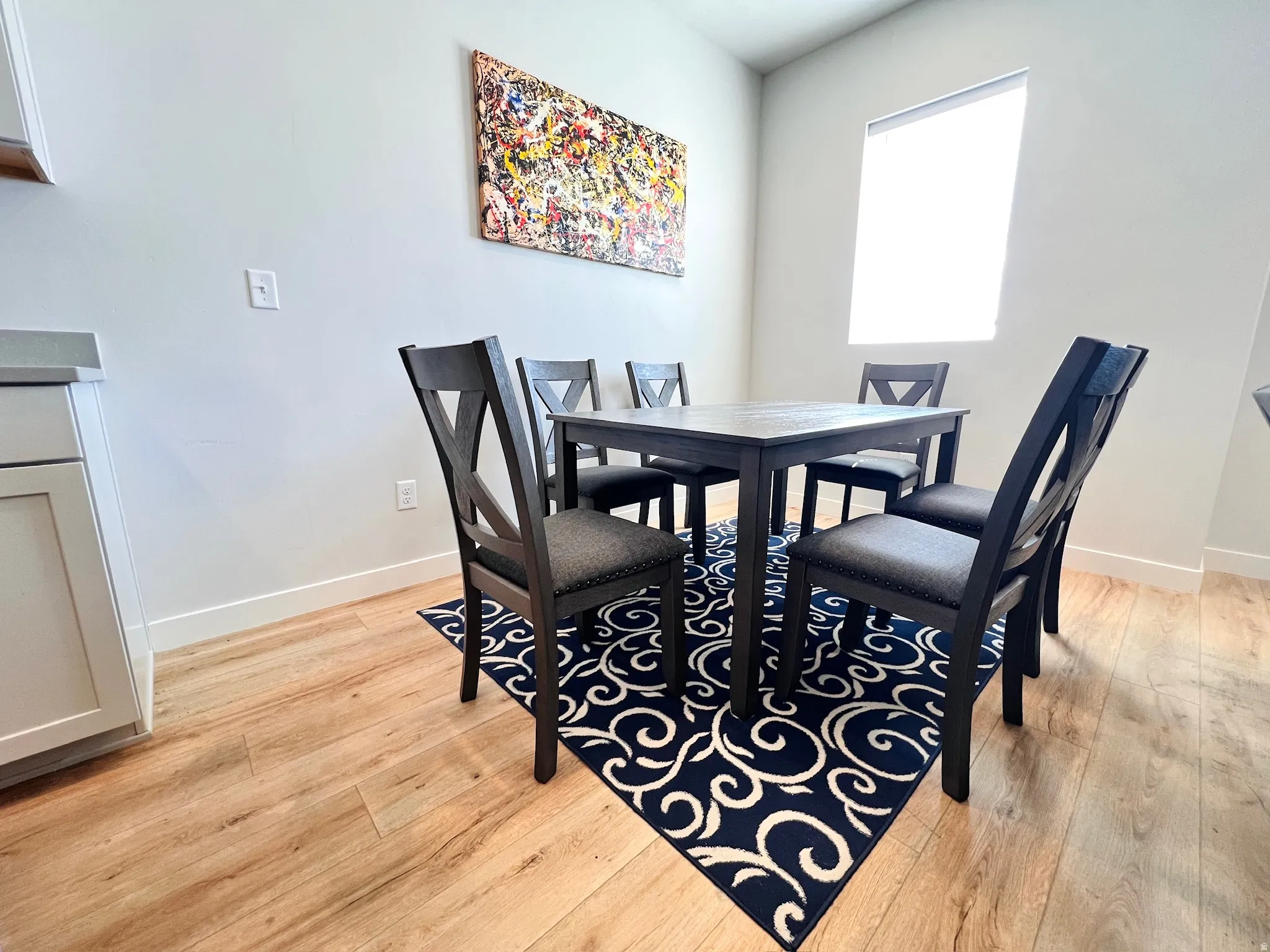 Dining area featuring wood-finish flooring, a white trim baseboard, and a built-in window with blind