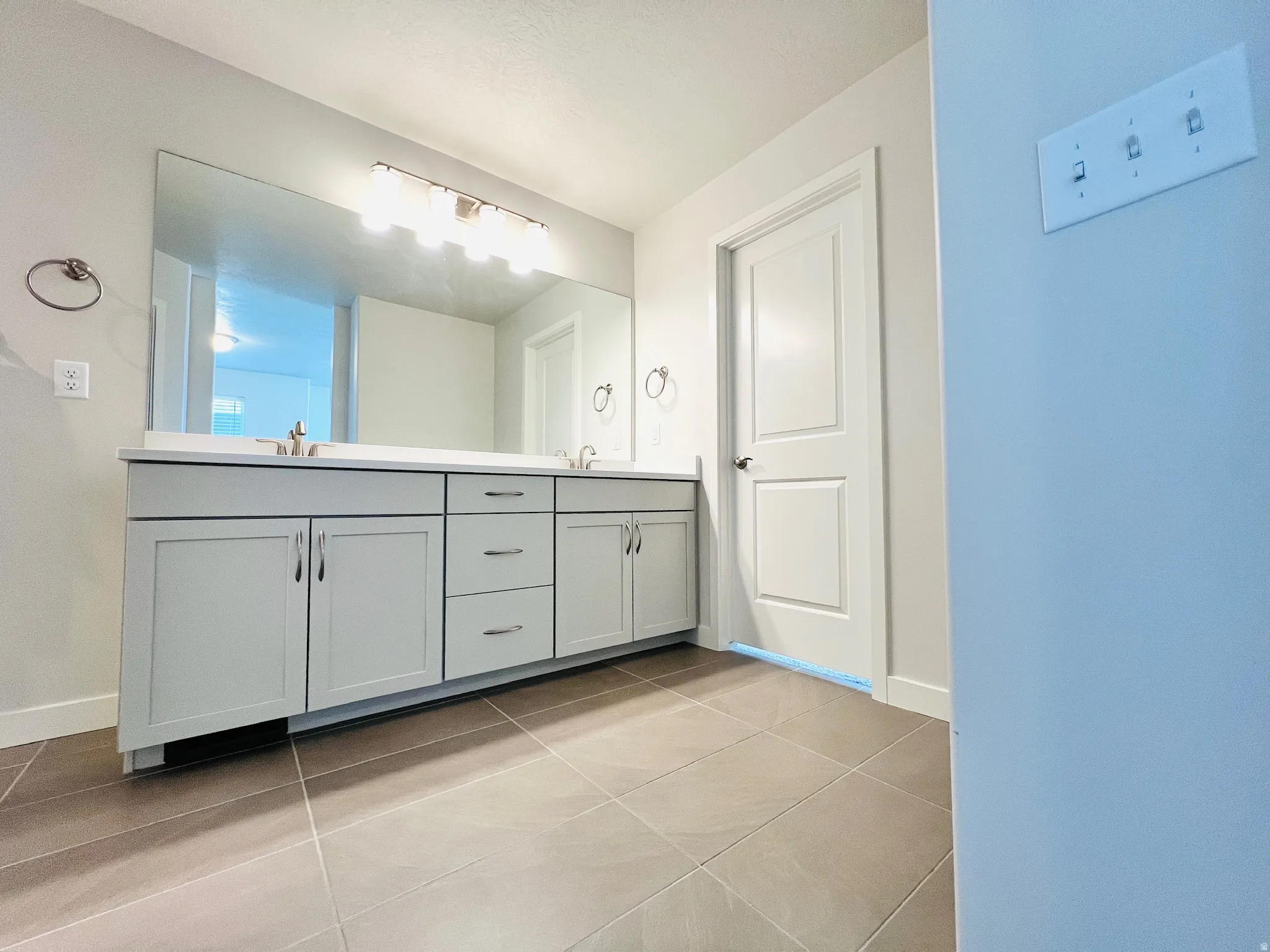 Spacious bathroom featuring a dual vanity with light gray cabinetry, a white countertop, and integrated sinks