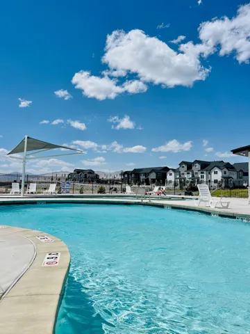 Outdoor swimming pool with concrete decking, a white shade structure, and lounge chairs