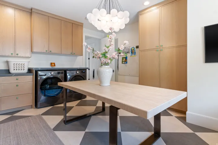 Utility room featuring extensive built-in cabinetry, dark stone countertops, and a modern spherical chandelier