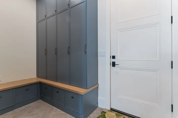 Custom cabinetry featuring floor-to-ceiling storage and lower drawers, complemented by a light wood-finish benchtop