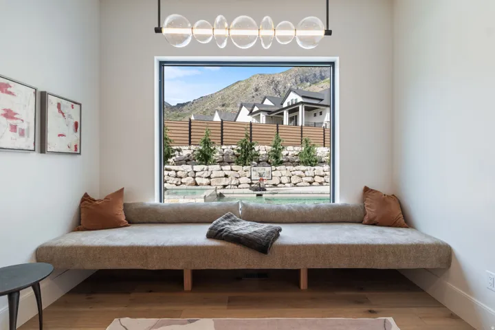 Built-in window bench with a modern linear chandelier and wood-finish flooring