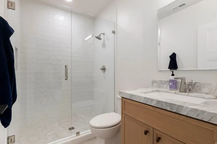 Walk-in shower with clear glass enclosure and tiled walls