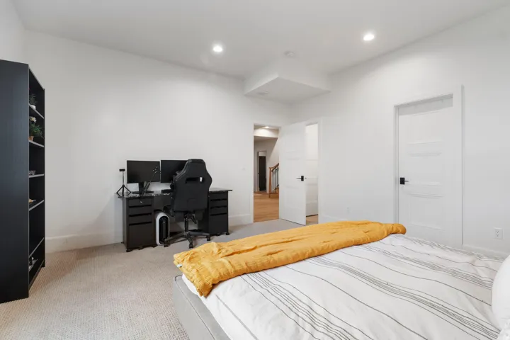 Bright bedroom featuring recessed lighting, a neutral carpet, white walls, and a white panel door with matte black hardware