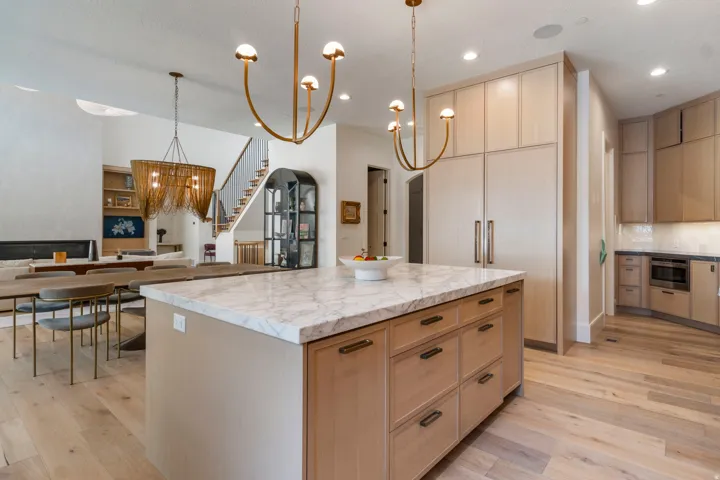 Expansive kitchen island with a marble countertop and white oak cabinetry