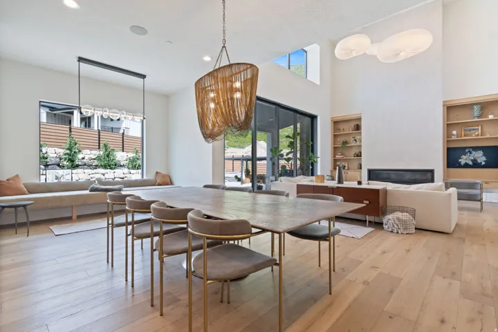Spacious open-concept living area featuring light wood-finish flooring, a contemporary fireplace, and a high vaulted ceiling