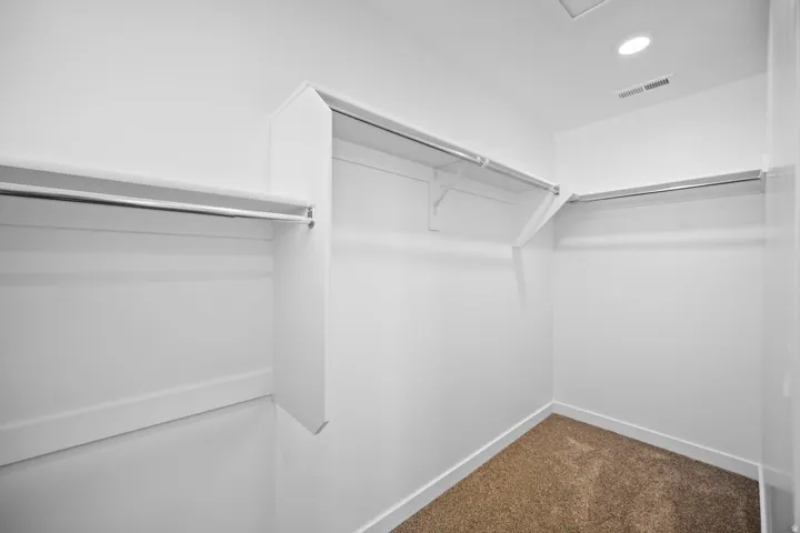 Walk-in closet featuring white walls, white trim, recessed lighting, and carpet flooring