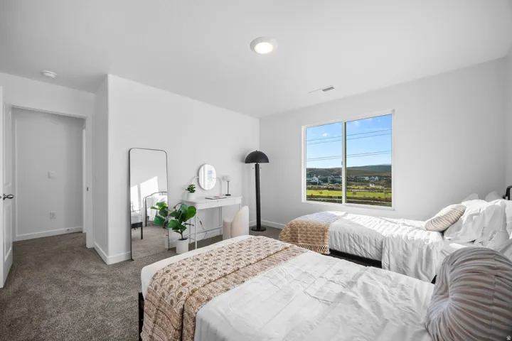 Bedroom featuring neutral carpeting, white walls, and a large window overlooking a distant landscape