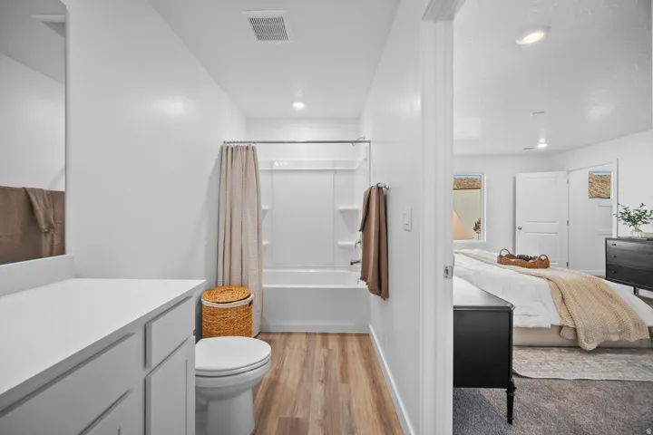 Bathroom featuring a bathtub with shower, toilet, and a white vanity with countertop