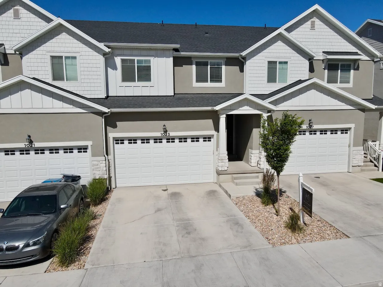 Modern townhome exterior featuring light gray stucco and white siding with decorative shingle accents