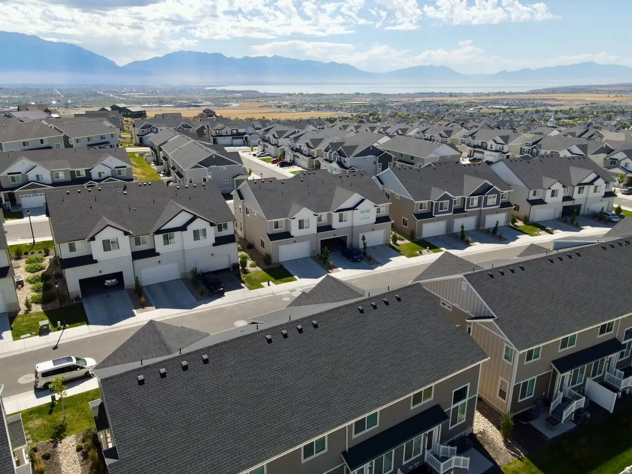 Aerial perspective showcasing a residential development with a mountain and water background