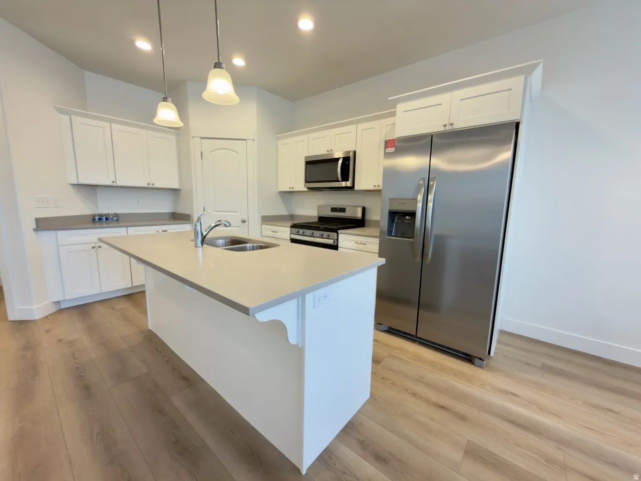 Contemporary kitchen featuring a central island with a double basin sink and pendant lighting
